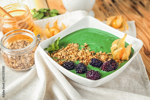 Dish with yummy spirulina smoothie on table. Healthy vegan food concept
