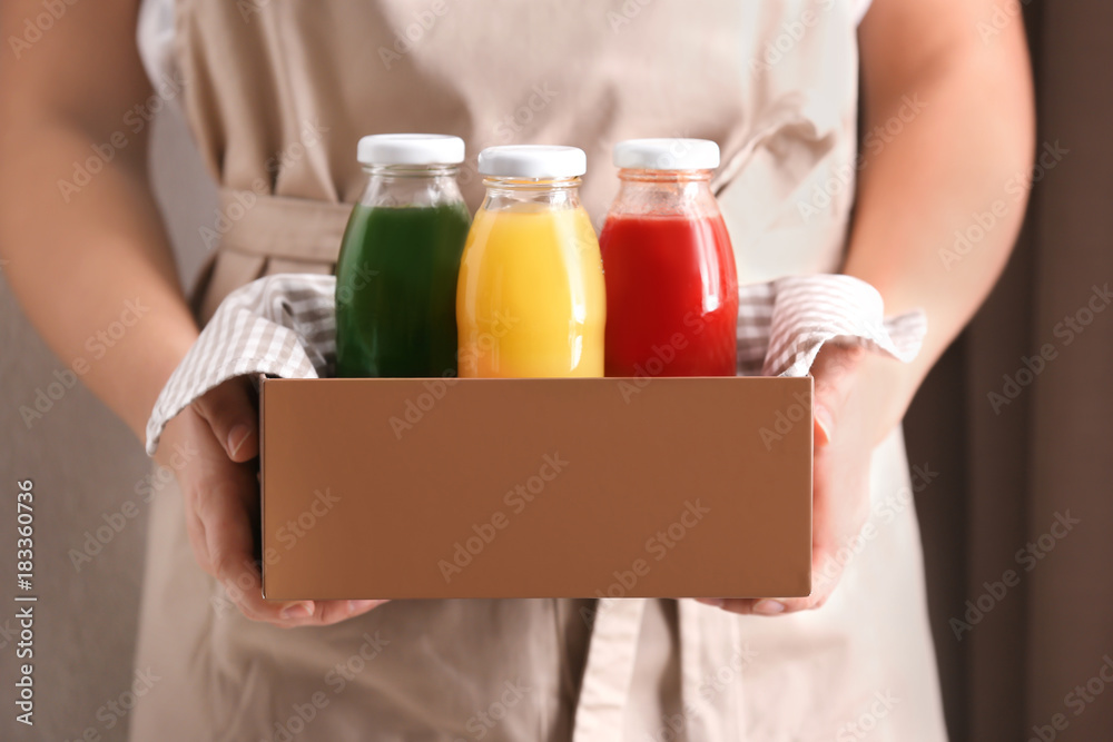 Woman holding wooden crate with delicious juices in bottles Woman holding wooden crate with delicious juices in bottles