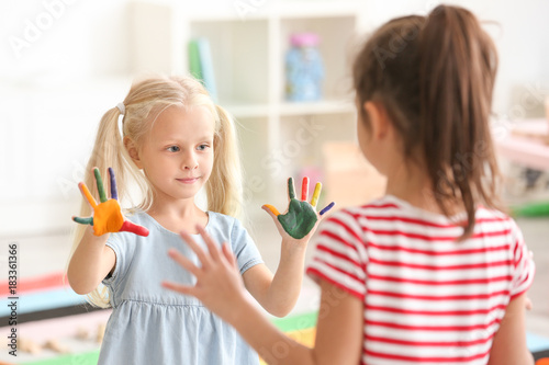 Cute little girls with painted hands in kindergarten