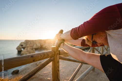 Man stretching at sunset on a cliff