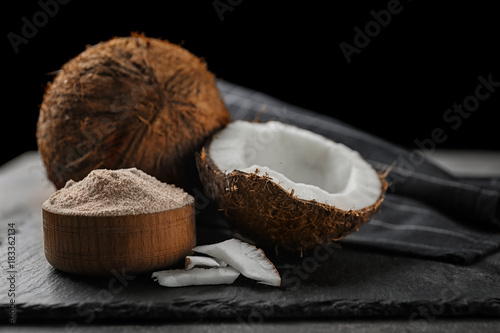 Wooden bowl with coconut flour and fresh nuts on table
