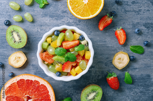 Composition with fruit salad on color background