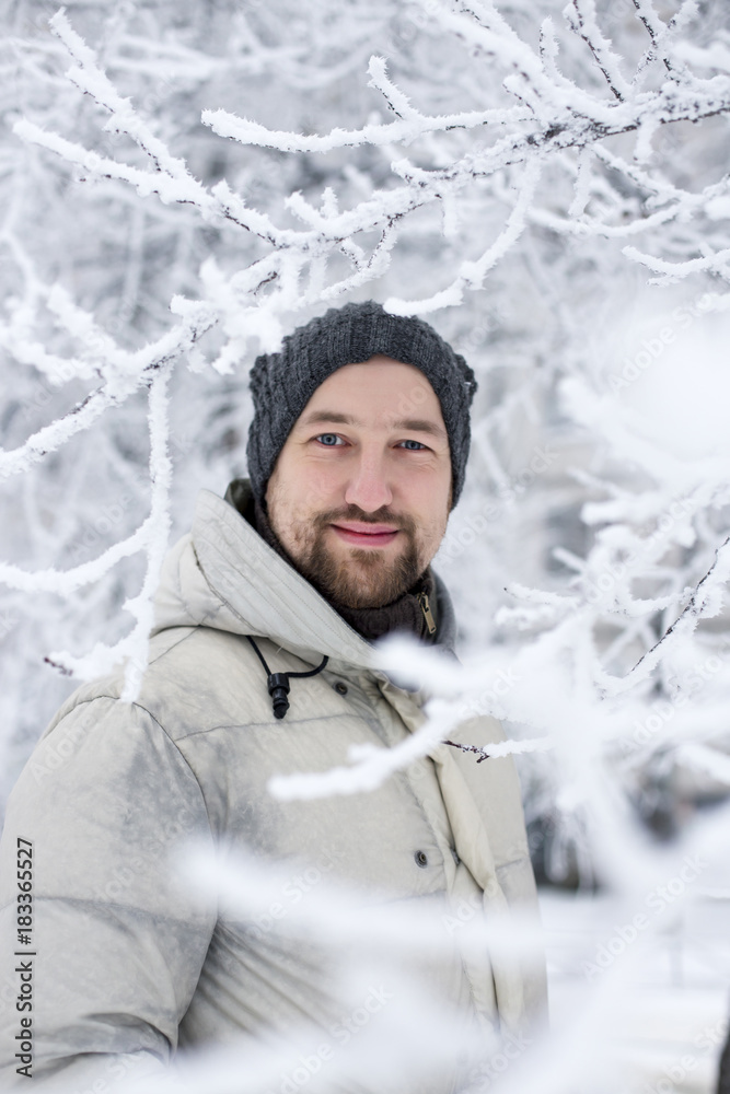 Joyful man wearing white jacket in the winter park. Joyful man wearing white jacket in the winter park.