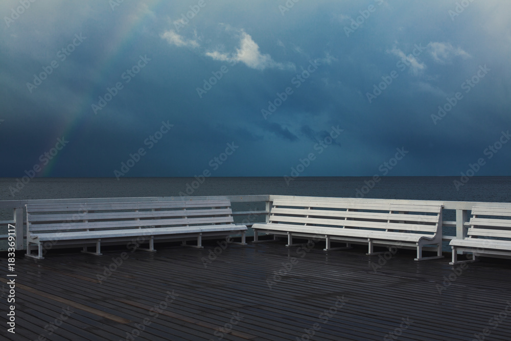 Place for rest and meditation concept. Beautiful view from white wooden pier on calm sea with rainbow. Stormy weather. Text-space. Sopot, Poland. Outdoor shot