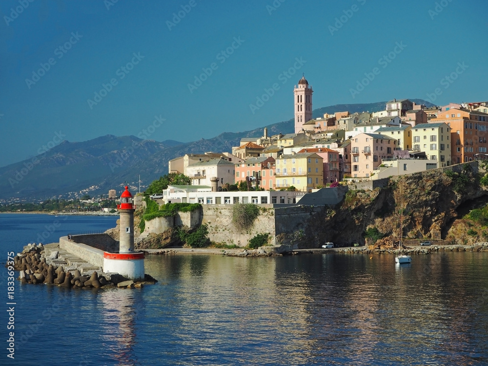 Corsica Bastia port view from sea on harbor with red lighthous church and old town blue sky background