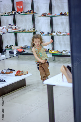 Little kid girl playing in a shoe store. Running from the shoe store.