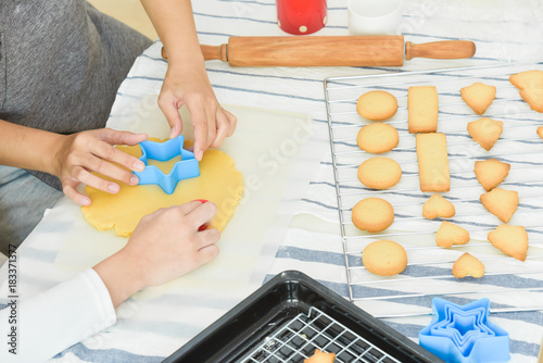 Asian girl and woman hands using cutters on dough.