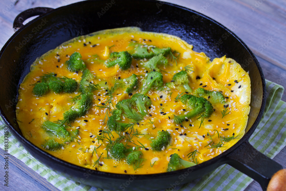 Omelette with broccoli and herbs, toasted with sesame seeds on frying pan, horizontal Omelette with broccoli and herbs, toasted with sesame seeds on frying pan, horizontal