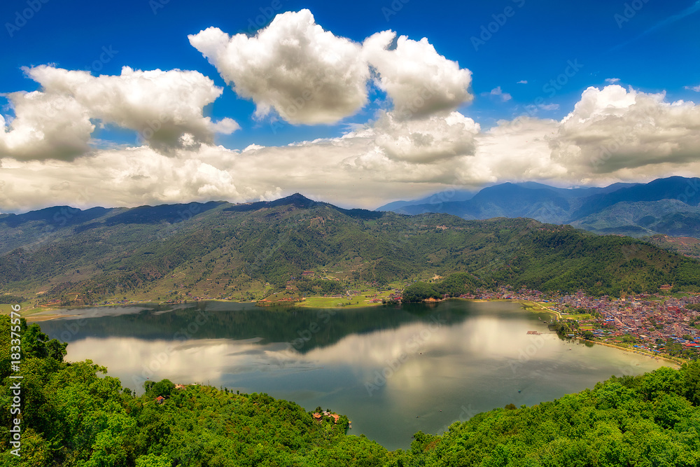 magical and majestic panoramic landscape of  mountain ranges and fewa(phewa) lake with reflections and blue sky and white clouds in pokara. nepal.