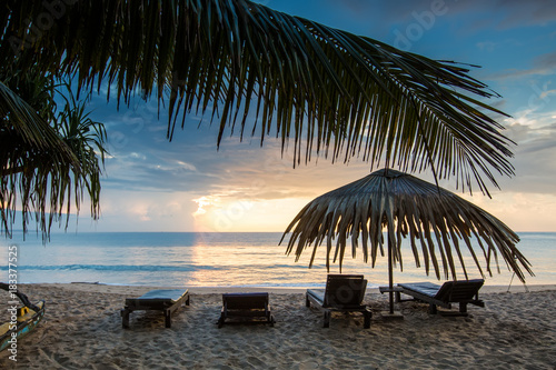 Sun loungers with umbrella on the beach, sunrise © Maygutyak