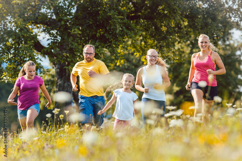 Familie beim Jogging über eine Wiese mit Blumen im Sommer als Sport