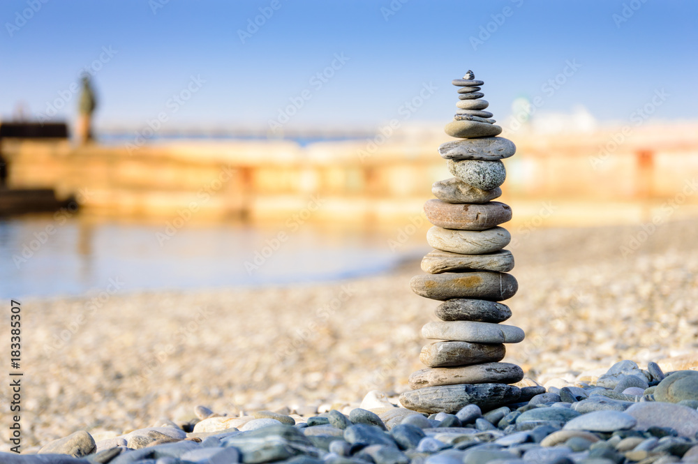 Fototapeta premium Pyramid of sea stones on pebbles of the sea shore. The concept of balance and spirituality.