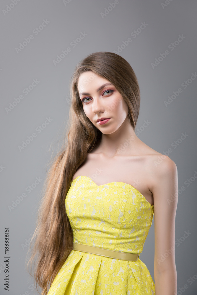 Emotional Girl with Sensual Lips on Grey Background. Portrait of Attractive Brunette in Yellow Bright Dress Emotional Girl with Sensual Lips on Grey Background. Portrait of Attractive Brunette in Yellow Bright Dress