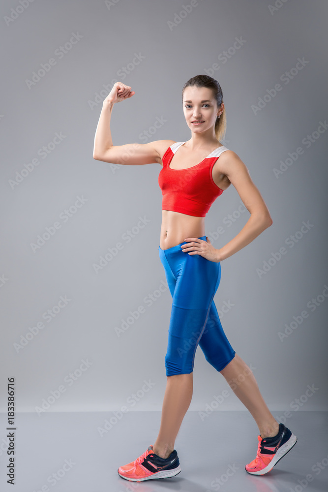 sport fitness woman flexing show her biceps muscles, young healthy smile  girl athletic body, perfect figure in gym Stock Photo