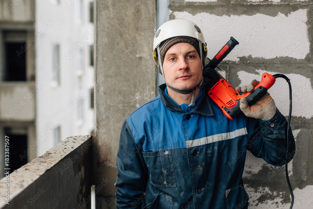 Construction worker in helmet and uniform with perforator. Man with drill Construction worker in helmet and uniform with perforator. Man with drill