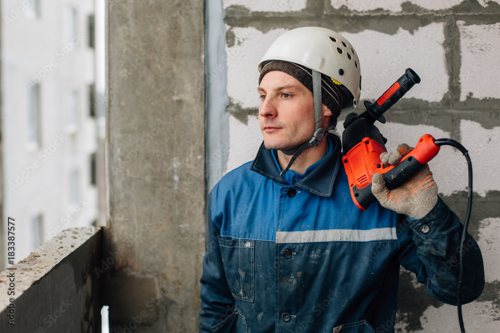 Construction worker in helmet and uniform with perforator. Man with drill Construction worker in helmet and uniform with perforator. Man with drill