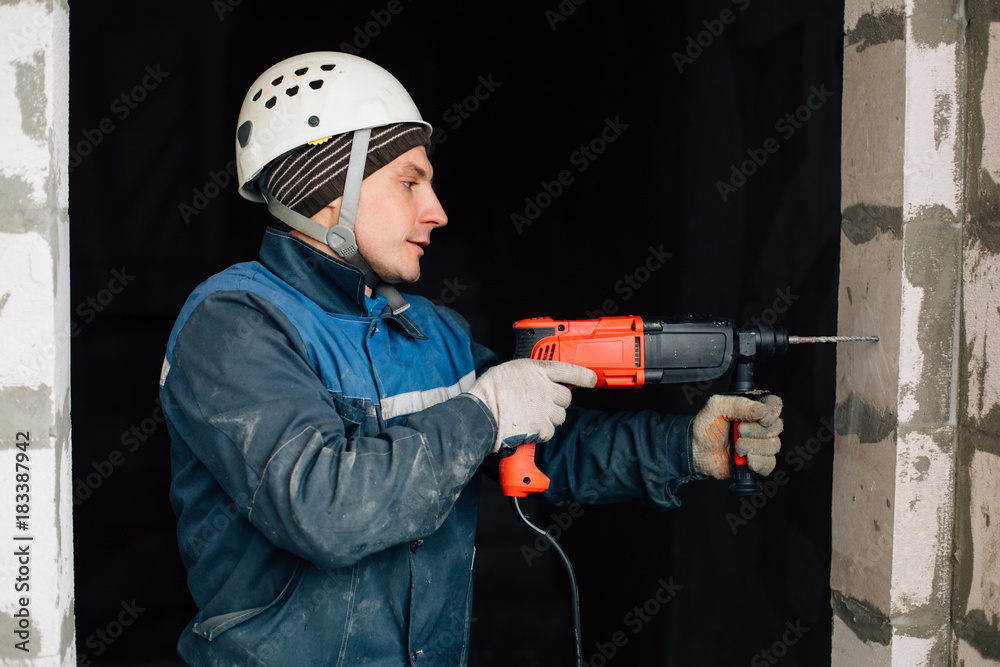Construction worker in helmet and uniform with perforator. Man with drill Construction worker in helmet and uniform with perforator. Man with drill