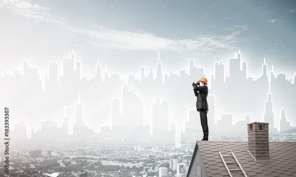 Engineer man standing on roof and looking in binoculars. Mixed m Engineer man standing on roof and looking in binoculars. Mixed m