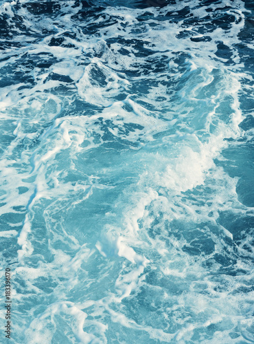 Pure blue turquoise water texture of the ocean sea with foam from and waves