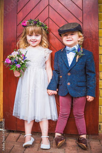 The little cheerful beautiful girl and boy standing near the door together