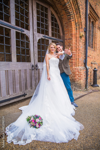 The young beautiful smiling newlyweds standing before the door of building outdoor and showing wedding rings on their fingers © Myroslava