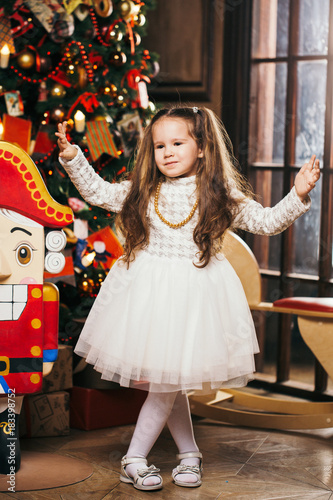 Cute little girl dancing near Christmas tree and nutcracker