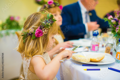 The beautiful little girl sitting by the table in restaurant and eating