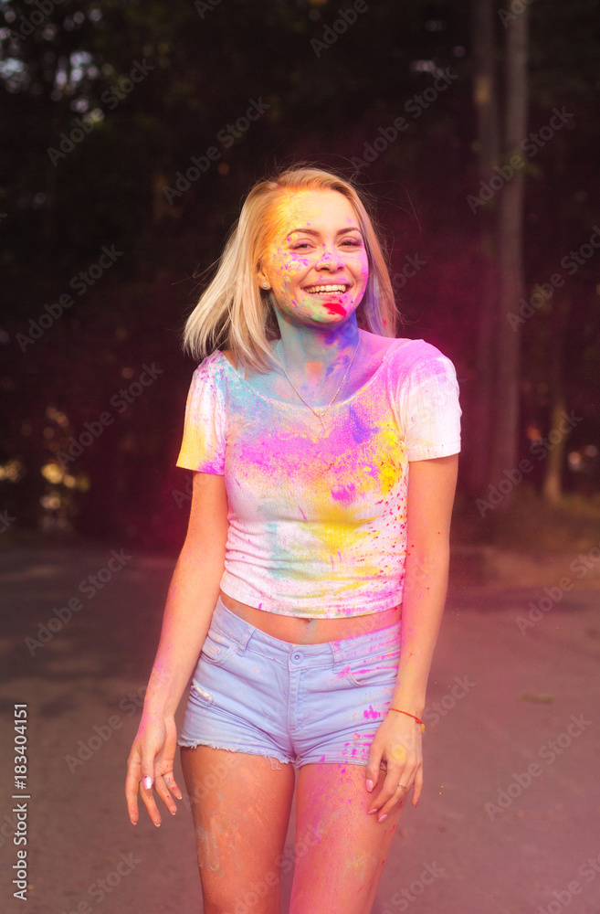 Positive young woman in white t shirt and jeans shorts on Holi festival in  the park Stock Photo | Adobe Stock
