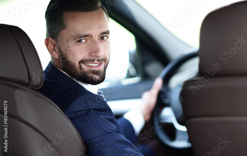 businessman sitting at the wheel of a car and looking at the camera © ASDF