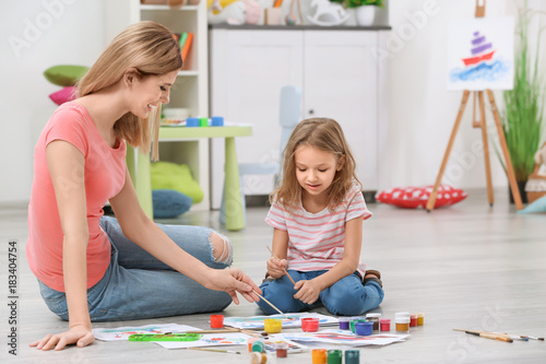 Mother with daughter painting while sitting on floor at home