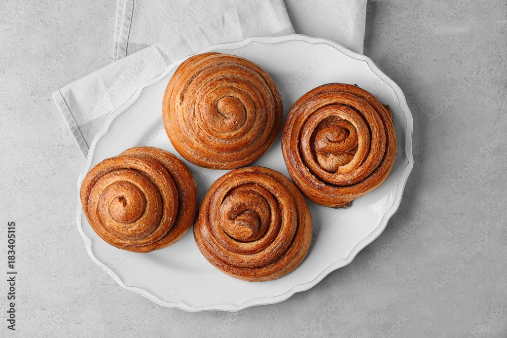 Fototapeta premium Plate with sweet cinnamon rolls on table