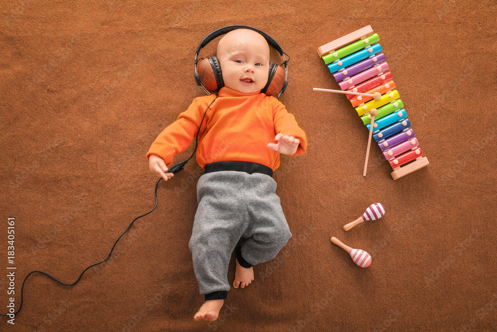 Naklejka premium Cute boy with headphones and xylophone on color textile