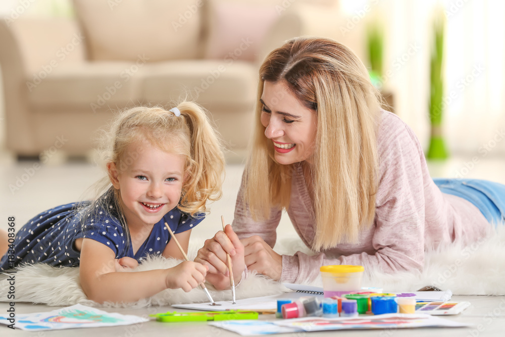 Mother with cute girl painting picture on sheet of paper, indoors Mother with cute girl painting picture on sheet of paper, indoors