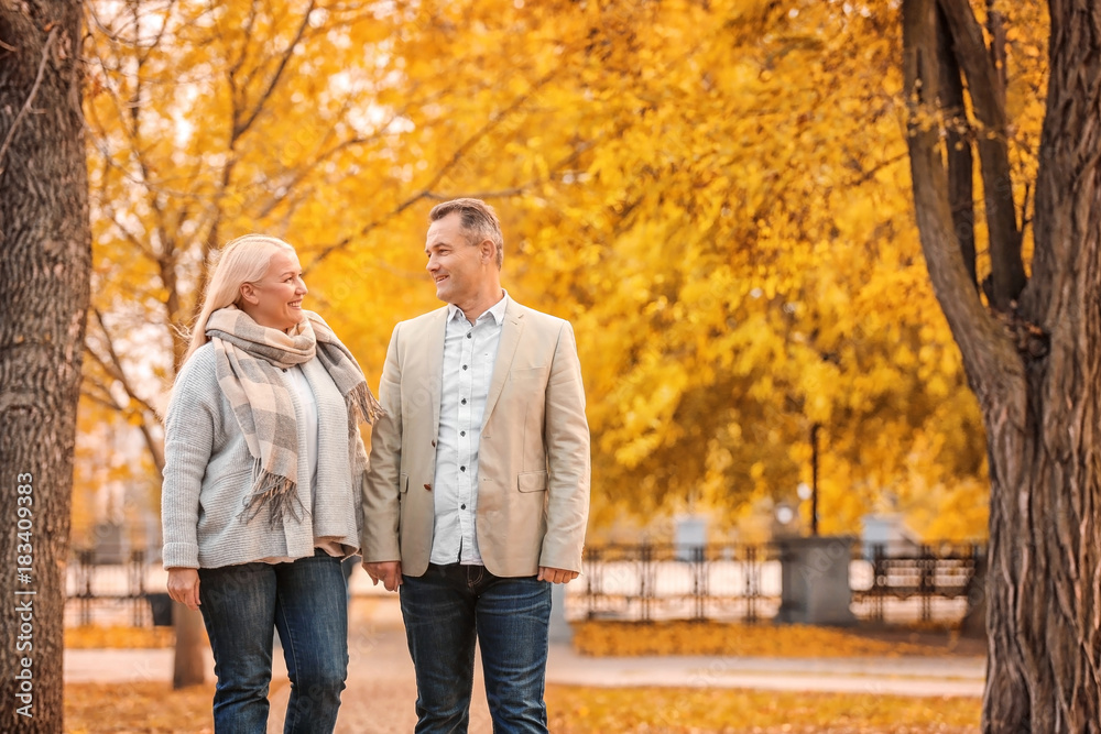 Mature couple walking in park on autumn day Mature couple walking in park on autumn day