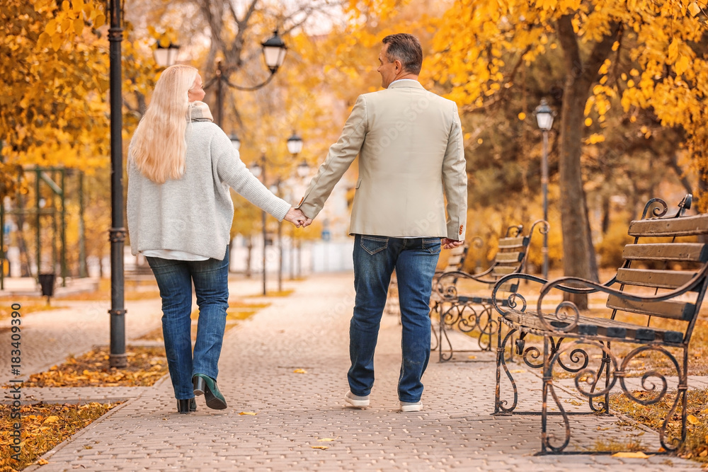 Mature couple walking in park on autumn day Mature couple walking in park on autumn day