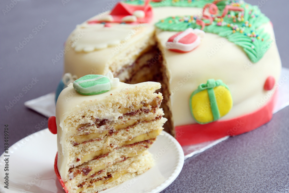 slice, portion of handmade decorated with sugar paste, fondant christmas cake: cut of banana and chocolate cake