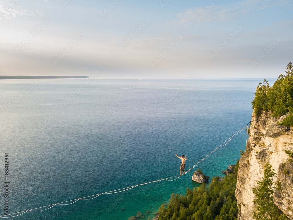 Man walking a high line slack line high above water