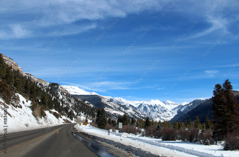 Scenic landscape with snow on road side and mountains ahead