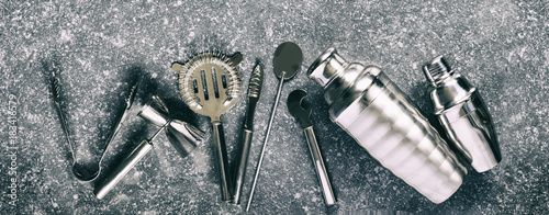 Set of bar tools for making a cocktails arranged on a stone background.
