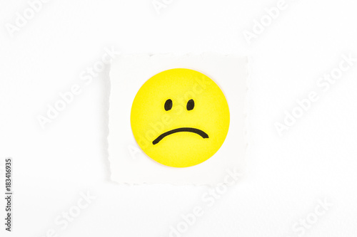 Frowning face emoji note message on white background paper desk