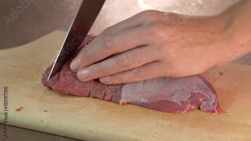 Woman cutting beef with a knife at home photo