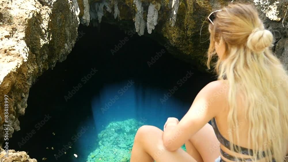 young attractive beautiful woman sitting in front of discovered cave with beautiful crystal clear water young attractive beautiful woman sitting in front of discovered cave with beautiful crystal clear water