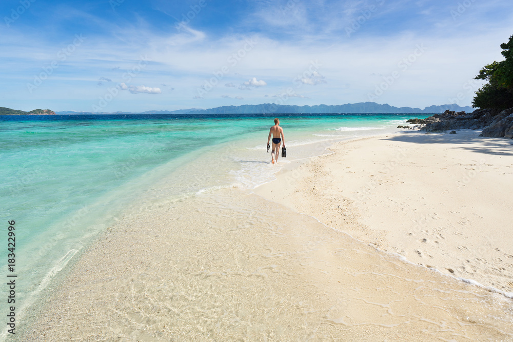 Man with snorkeling mask and flippers walking on the beautiful beach. Man with snorkeling mask and flippers walking on the beautiful beach.