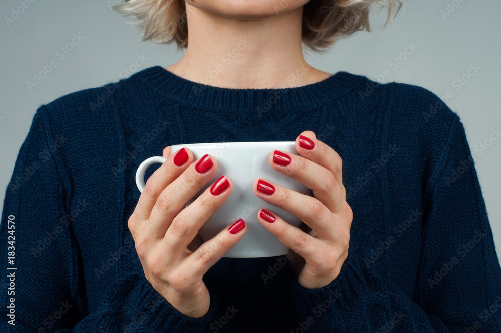 Woman in warm sweater is holding a cup of coffee. Woman in warm sweater is holding a cup of coffee.