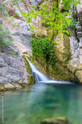 A small picturesque waterfall in a cozy mountain lagoon. photo