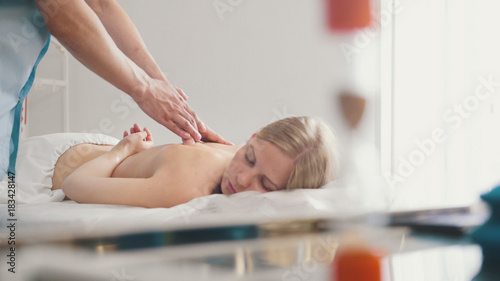 Male physiotherapist massaging woman's back in the medical office