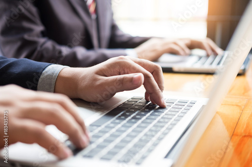 Businessman team working at office desk and using a digital computer laptop hands detail, computer and objects on the table.