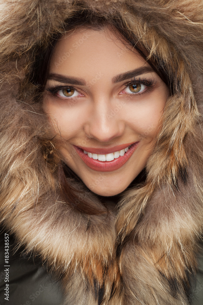 closeup of happy beautiful woman smiling with fur hood on closeup of happy beautiful woman smiling with fur hood on