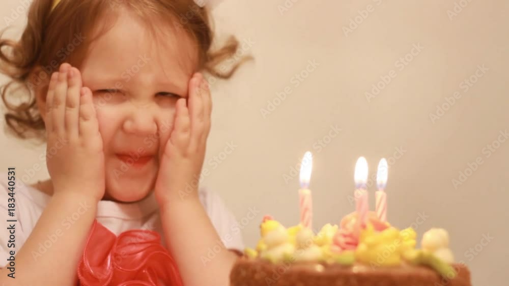 Portrait of a cute girl who makes a wish and blows out candles on her cake on her birthday 3 years. A smiling child and a happy childhood.