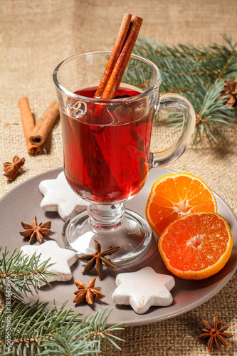 Glass of Christmas mulled wine with spices and cookies, orange on plate